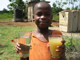 Child in Africa holding two glasses of water; one raw and one filtered through a SkyHydrant